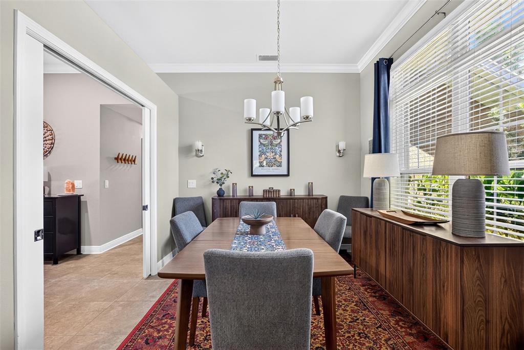 A dining room features a wooden table, grey upholstered chairs, a sideboard, and a patterned rug — 1667 MADISON AVENUE, NORTH PORT, FL