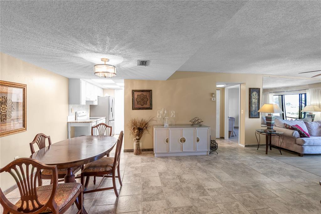 A dining area with a wooden table and chairs sits adjacent to a tiled kitchen — 4119 61ST AVENUE TERRACE W UNIT 102, BRADENTON, FL