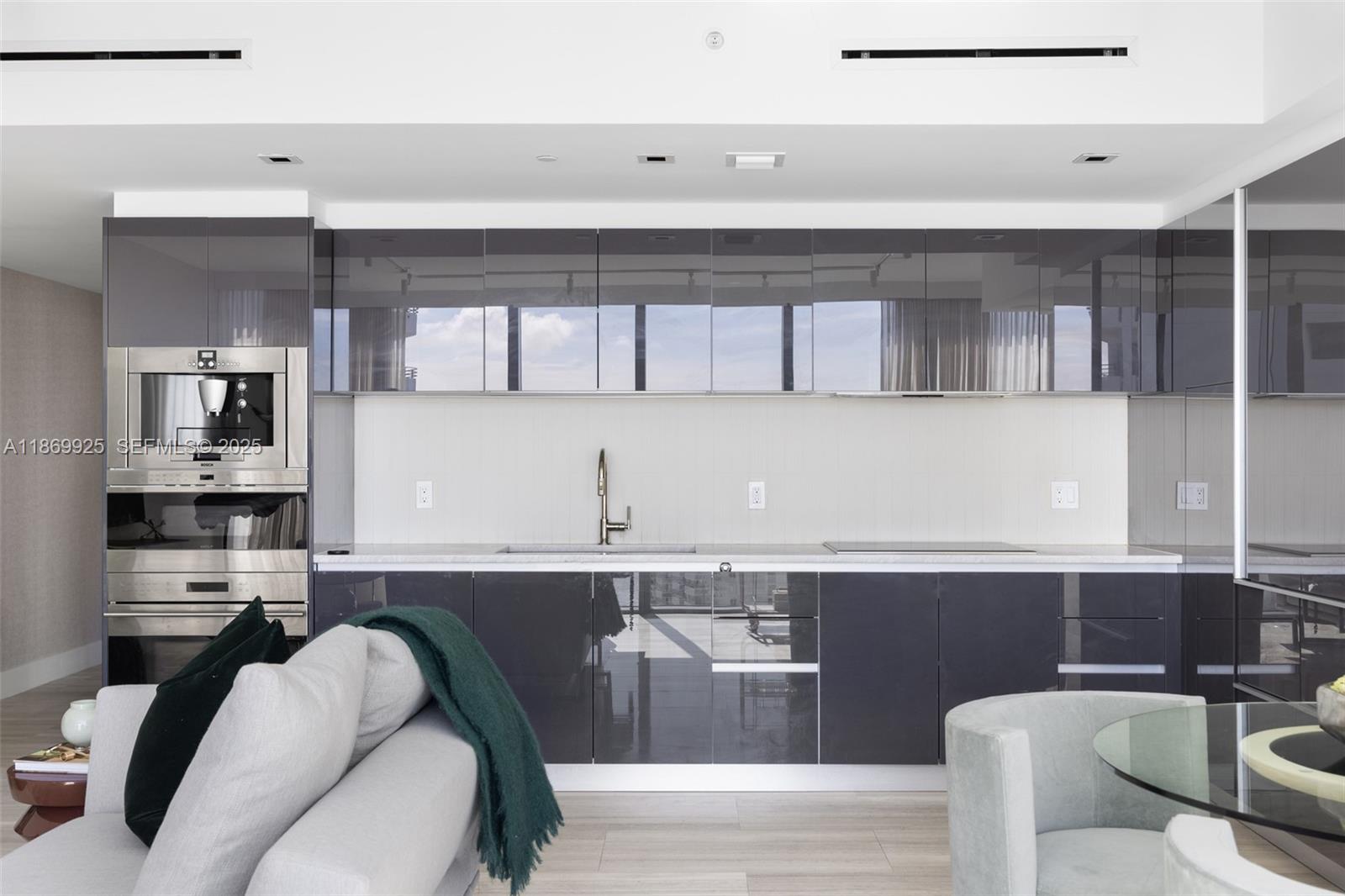 A modern kitchen features dark glossy cabinets, stainless steel appliances, and a light-colored countertop — 1451 Brickell Ave # 1901, Miami FL 33131, MIAMI, FL