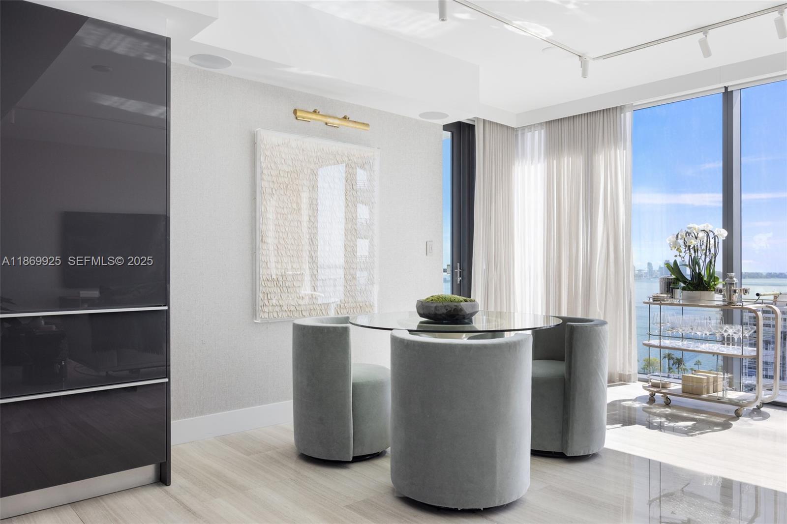A modern dining area features a glass table, three velvet chairs, and a bar cart — 1451 Brickell Ave # 1901, Miami FL 33131, MIAMI, FL