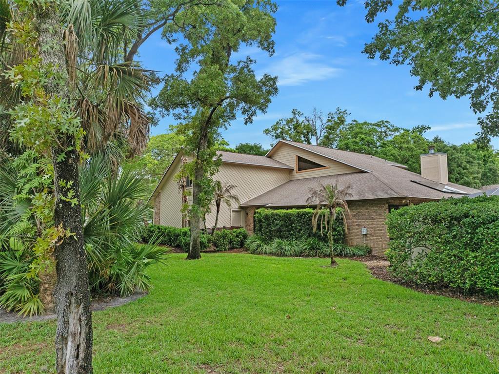 A two-story house with tan siding and brick exterior sits on a grassy lawn — 1 CROOKED BRIDGE WAY, ORMOND BEACH, FL