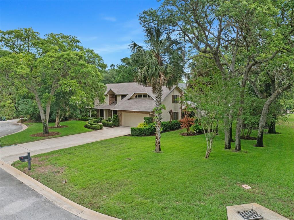 A two-story house with a beige exterior, a two-car garage, and a large grassy yard — 1 CROOKED BRIDGE WAY, ORMOND BEACH, FL