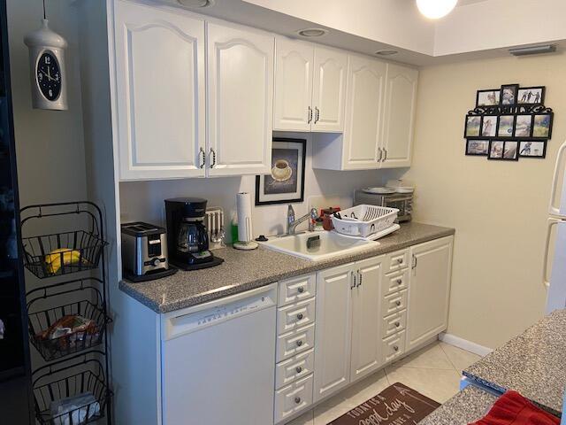 A kitchen features white cabinets, granite countertops, a dishwasher, and a sink — 4042 Exeter C, Boca Raton FL 33434, BOCA RATON, FL
