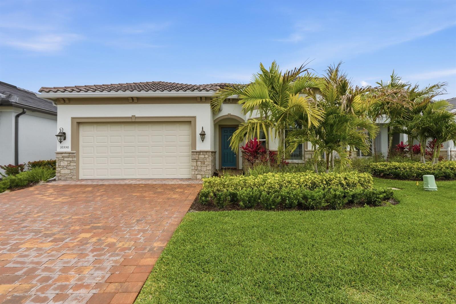 A single-story house with a beige garage, stone accents, and palm trees in the front yard — 10550 Northbrook Circle, Palm Beach Gardens FL 33412, PALM BEACH GARDENS, FL