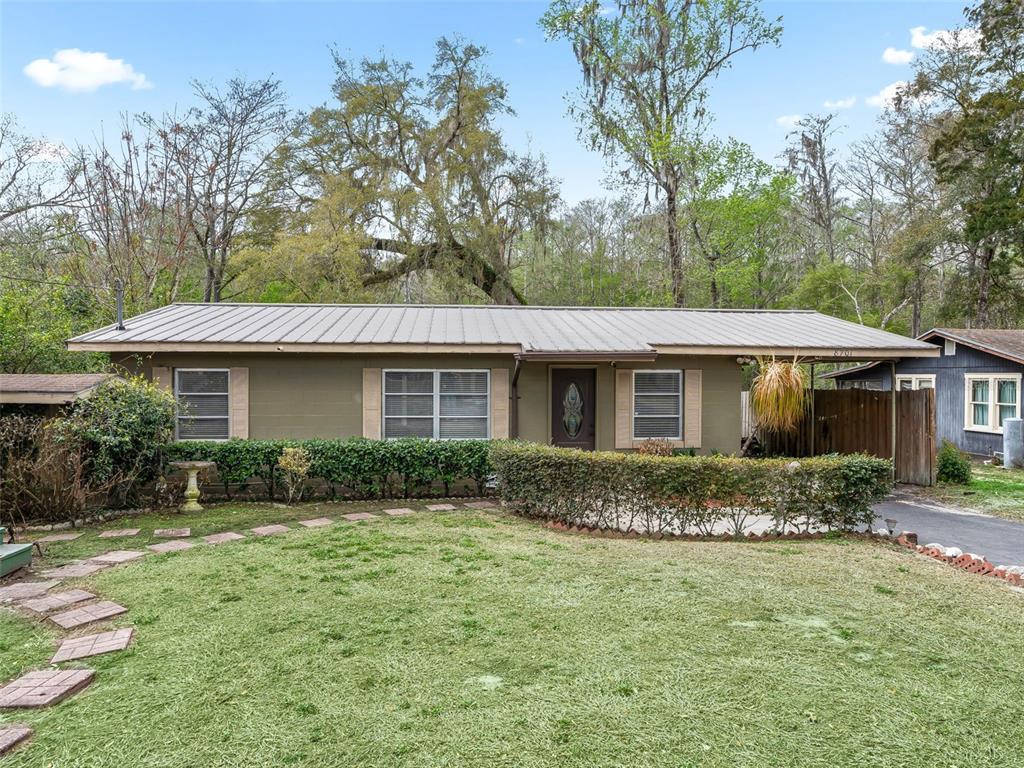 An aerial view shows a house with a driveway on a long, rectangular, tree-lined lot — 8701 CR 647 S, BUSHNELL, FL