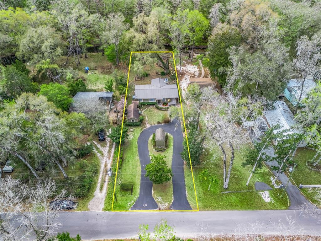 An aerial view shows a house with a circular driveway on a wooded lot — 8701 CR 647 S, BUSHNELL, FL