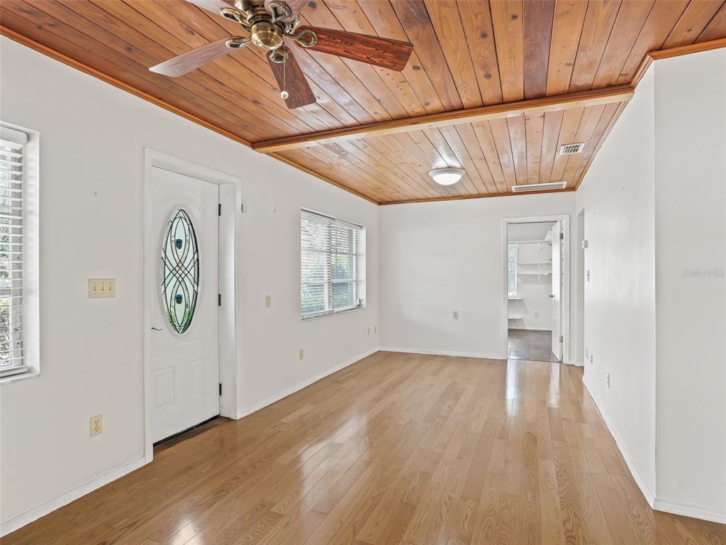 A room with light wood floors, white walls, and a wood-paneled ceiling with a fan — 8701 CR 647 S, BUSHNELL, FL