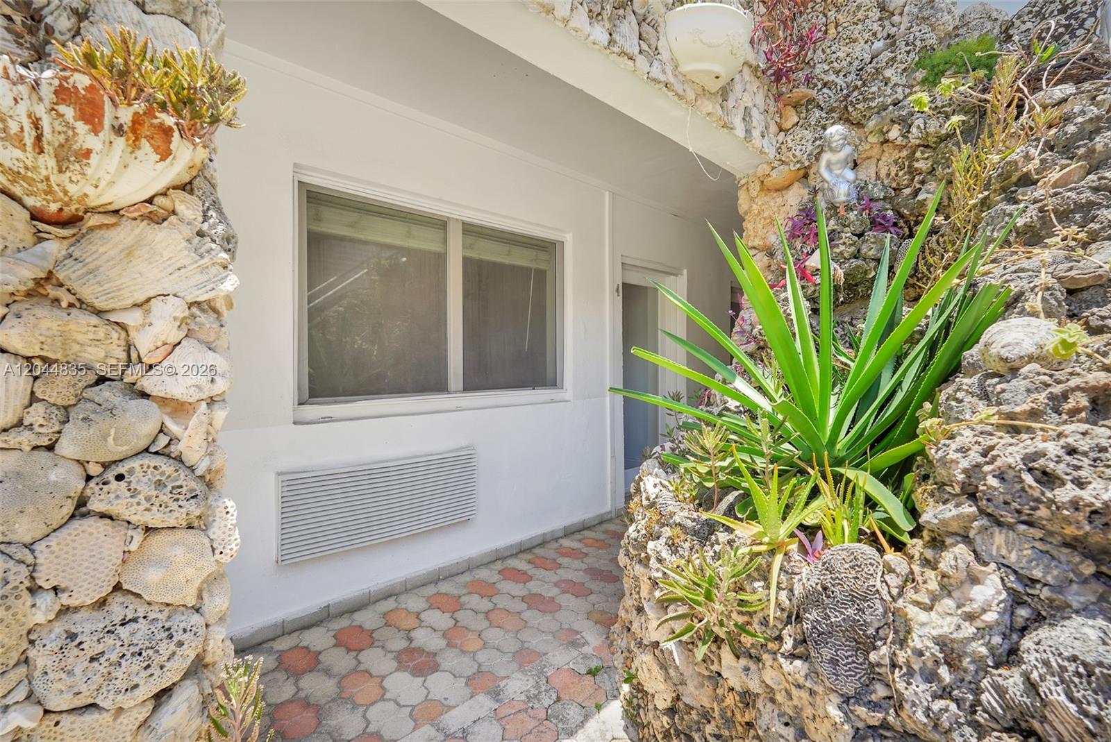 An exterior view shows a walkway with patterned pavers leading to a doorway and window — 320 85th St # 4, Miami Beach FL 33141, MIAMI BEACH, FL