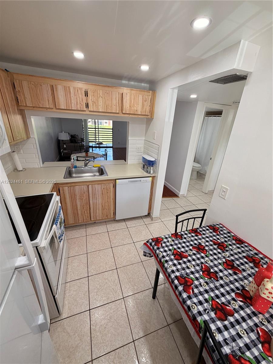 A kitchen features light wood cabinets, a white dishwasher, a tile floor, and a dining table — 2793 NW 104th Ave # 204, Sunrise FL 33322, SUNRISE, FL