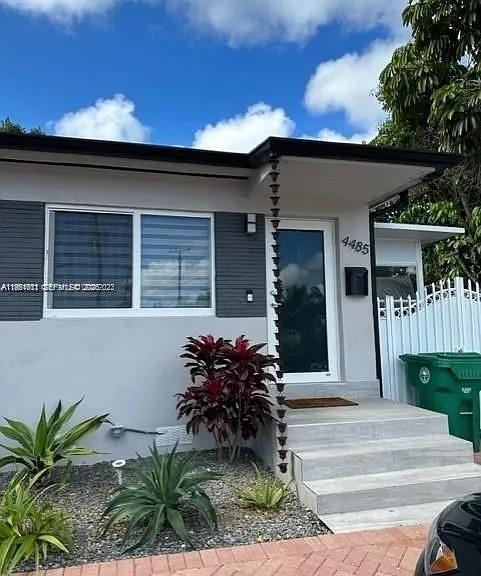 The exterior of a house features a gray facade, a glass front door, and concrete steps — 4485 SW 7th St, Miami FL 33134, MIAMI, FL