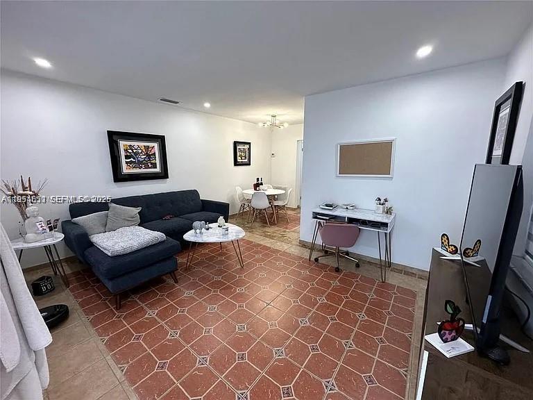 A living room features a dark blue sectional sofa, a small desk, and tiled floors — 4485 SW 7th St, Miami FL 33134, MIAMI, FL