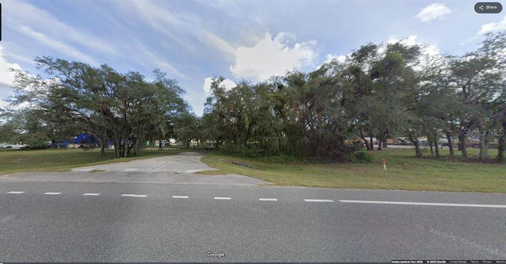 A paved driveway leads into a wooded, undeveloped lot from a paved road — N/A, POLK CITY, FL