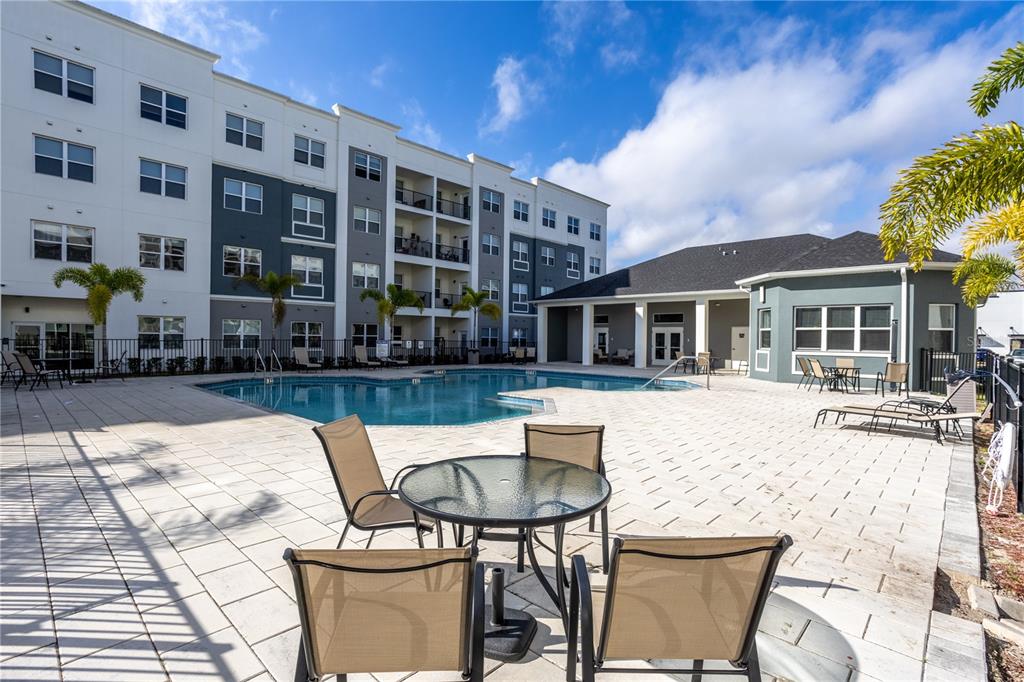 A swimming pool sits on a paved patio surrounded by a multi-story apartment building — 1230 SOUTHSTATION PLACE UNIT 306, ORLANDO, FL