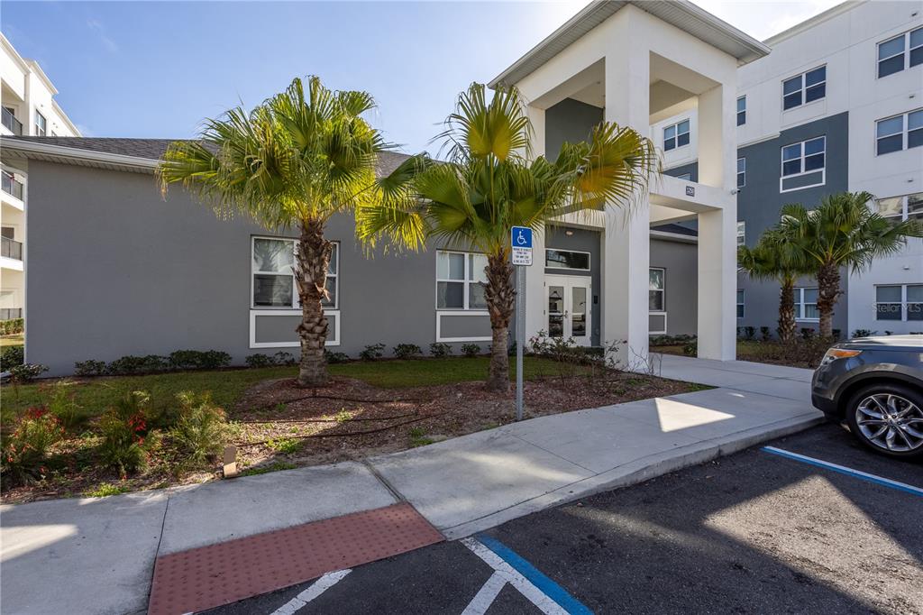 A gray apartment building exterior features a covered entrance, palm trees, and a handicap sign — 1230 SOUTHSTATION PLACE UNIT 306, ORLANDO, FL