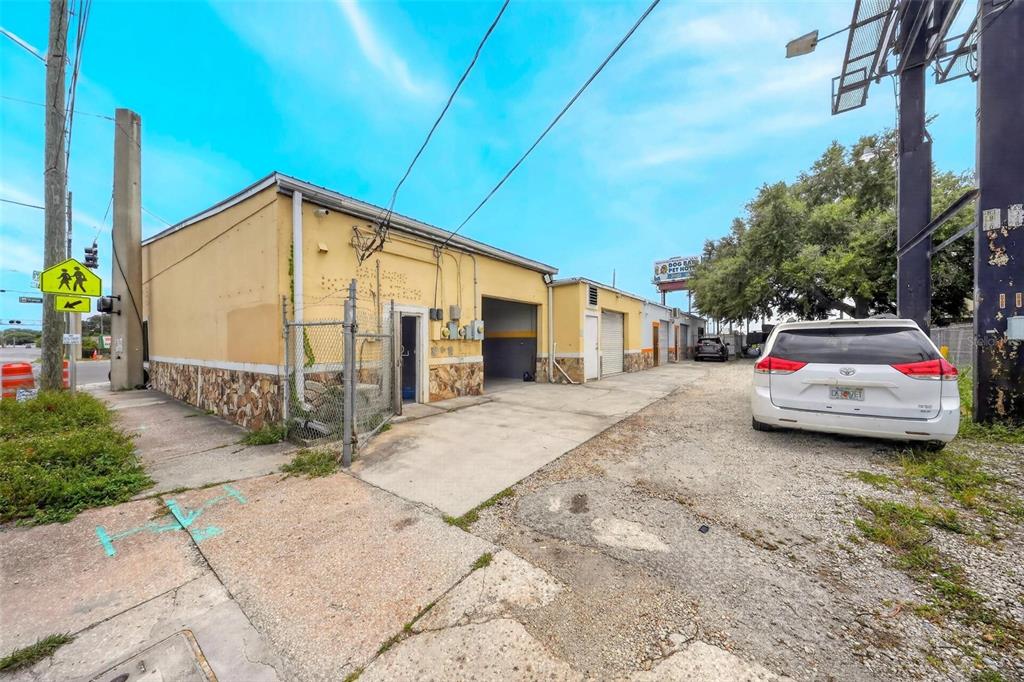 An exterior view of a single-story commercial building with a gravel lot and white SUV — 2906 N ORANGE BLOSSOM TRAIL, ORLANDO, FL