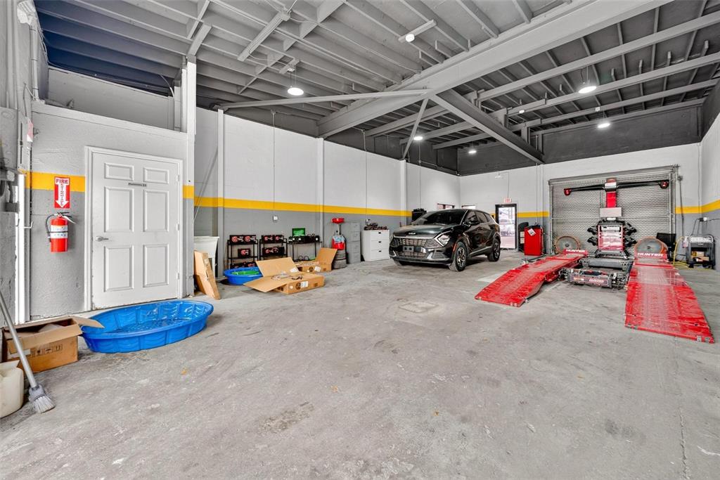 An auto repair shop features a concrete floor, exposed ceiling, and a vehicle alignment rack — 2906 N ORANGE BLOSSOM TRAIL, ORLANDO, FL