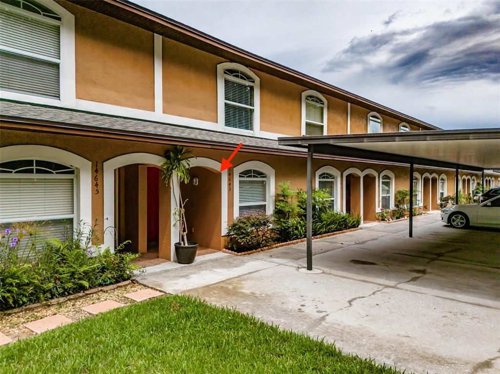 A two-story townhouse exterior features a covered carport, arched entryways, and a concrete driveway — 14643 PAR CLUB CIRCLE UNIT 14643, TAMPA, FL