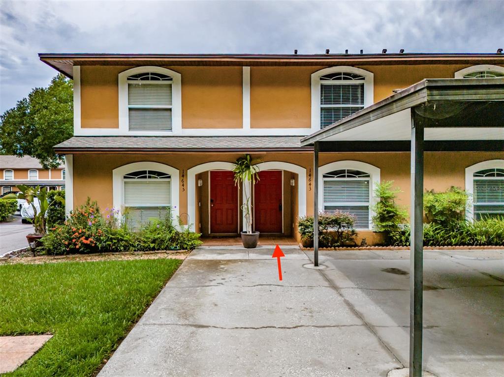 The exterior of a two-story townhouse features a concrete driveway and two red front doors — 14643 PAR CLUB CIRCLE UNIT 14643, TAMPA, FL