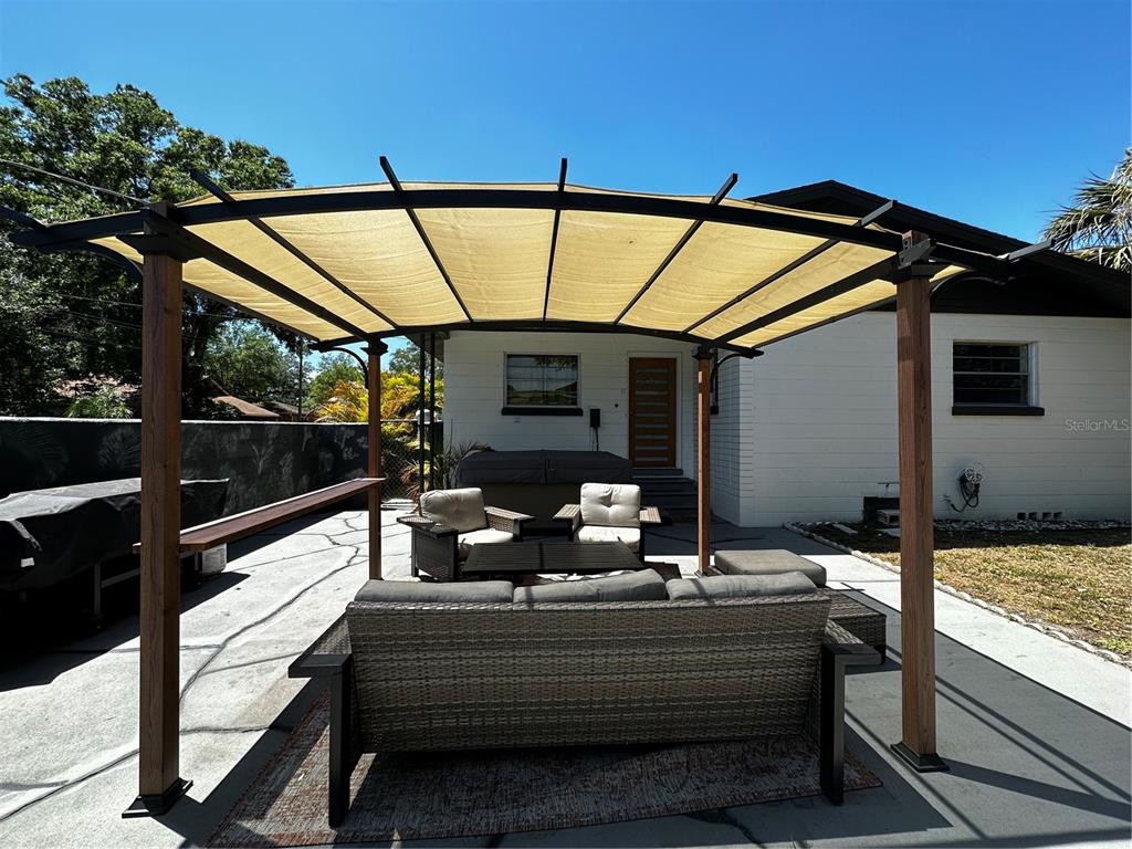 A patio features a large pergola with a fabric canopy over outdoor lounge furniture — 4701 N WILLIS STREET, TAMPA, FL