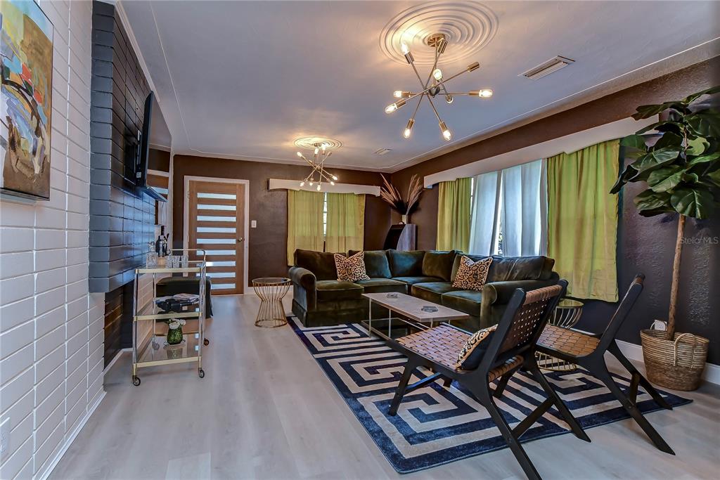 A living room features a dark green sectional sofa, a patterned rug, and two modern chairs — 4701 N WILLIS STREET, TAMPA, FL