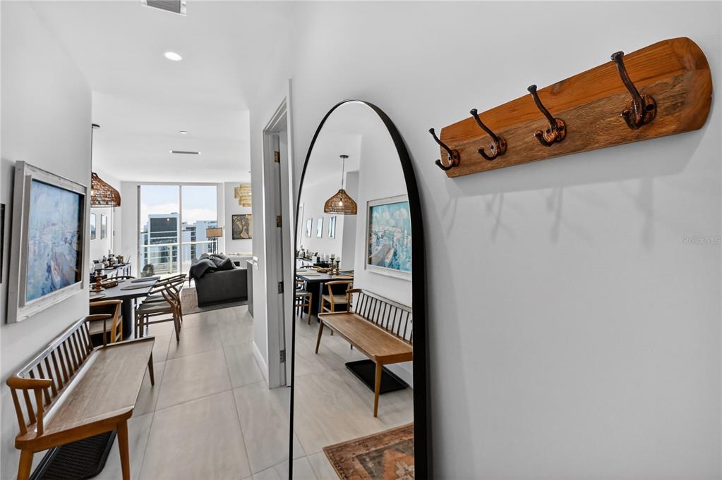 A hallway features a wooden coat rack, a tall arched mirror, and a wooden bench — 301 QUAY COMMONS UNIT 1807, SARASOTA, FL