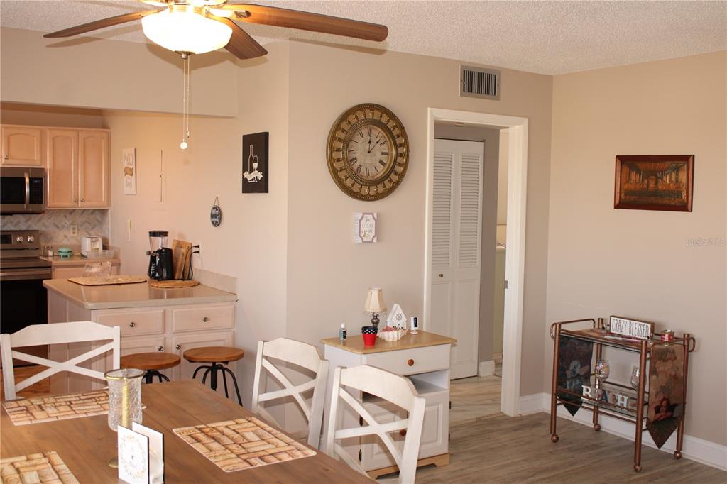 A dining area with a wooden table, white chairs, a kitchen, and a bar cart — 4460 IRONWOOD CIRCLE UNIT 501A, BRADENTON, FL