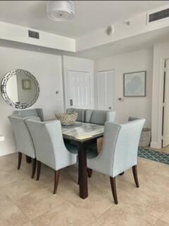 A dining area features a dark wood table, light blue upholstered chairs, and a round mirror — 700 E Boynton Beach Boulevard E # 1509, Boynton Beach FL 33435, BOYNTON BEACH, FL