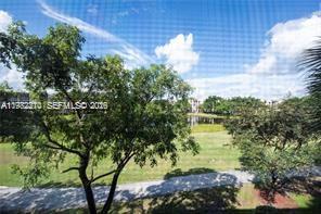 A view of a grassy field, a small pond, and trees seen through a window screen — 1713 Whitehall Dr # 302, Davie FL 33324, DAVIE, FL