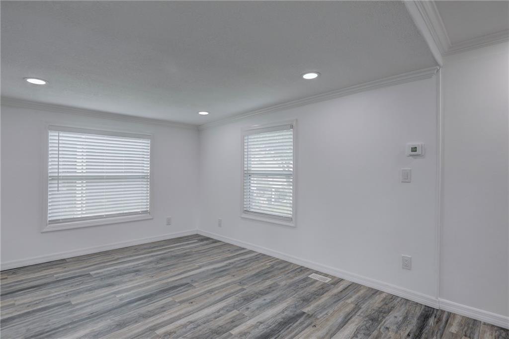 An empty room features white walls, recessed lighting, crown molding, and gray wood-look flooring — BAREFOOT BAY, FL