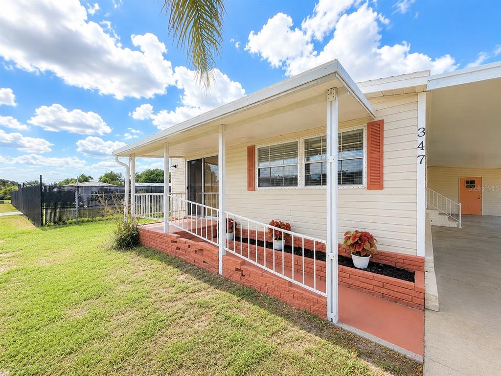 A single-story house with light siding, a brick planter, and a covered front porch — 347 CANAL COURT, LAKE WALES, FL