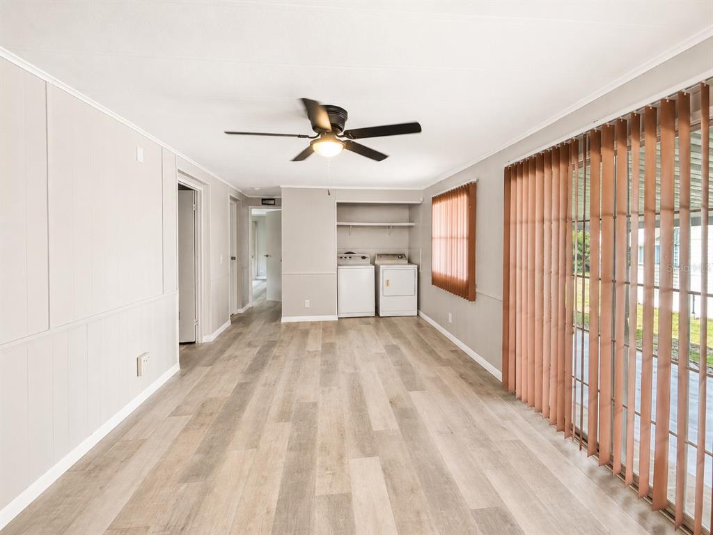 A room with light wood-look flooring, a ceiling fan, and a laundry area with appliances — 347 CANAL COURT, LAKE WALES, FL