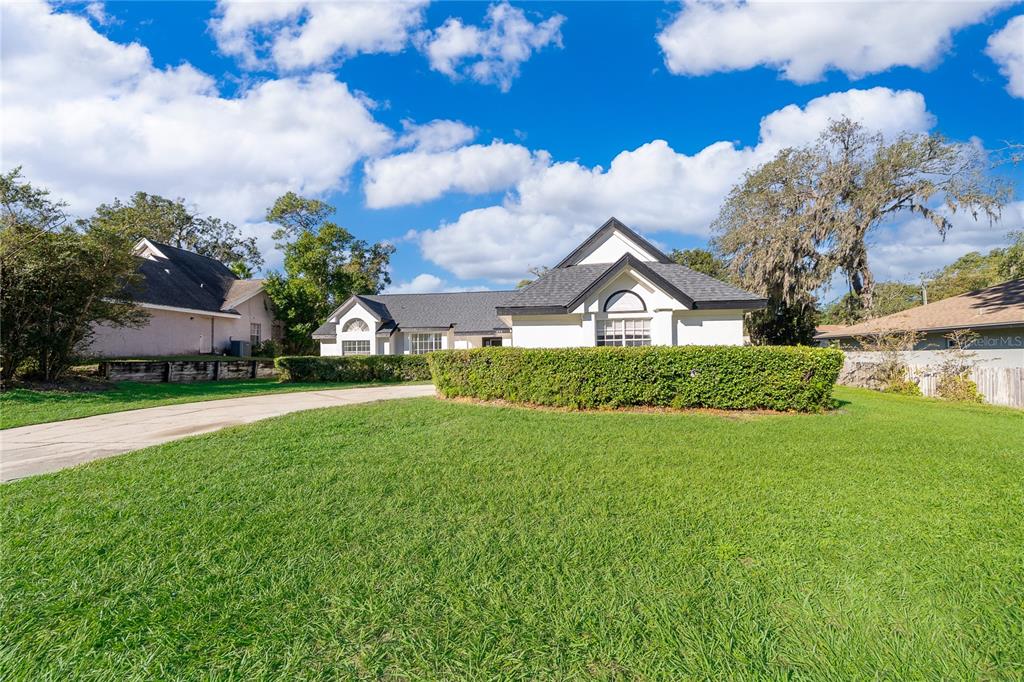 A single-story house with a white exterior, dark roof, and a curved concrete driveway — 1250 GLENMORE DRIVE, APOPKA, FL