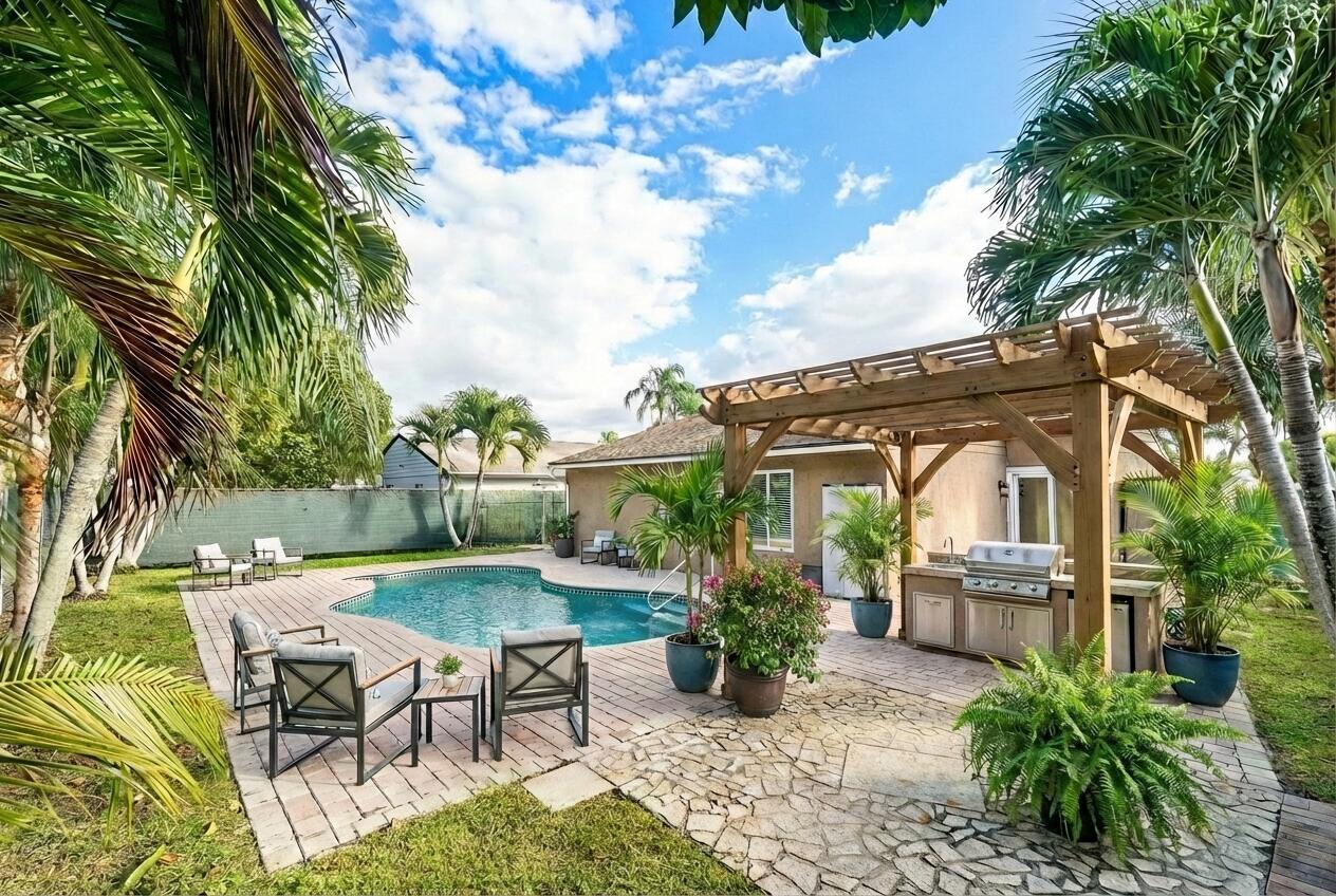 A backyard patio features a swimming pool, a wooden pergola, and an outdoor kitchen area — 8411 Garden Gate Place, Boca Raton FL 33433, BOCA RATON, FL