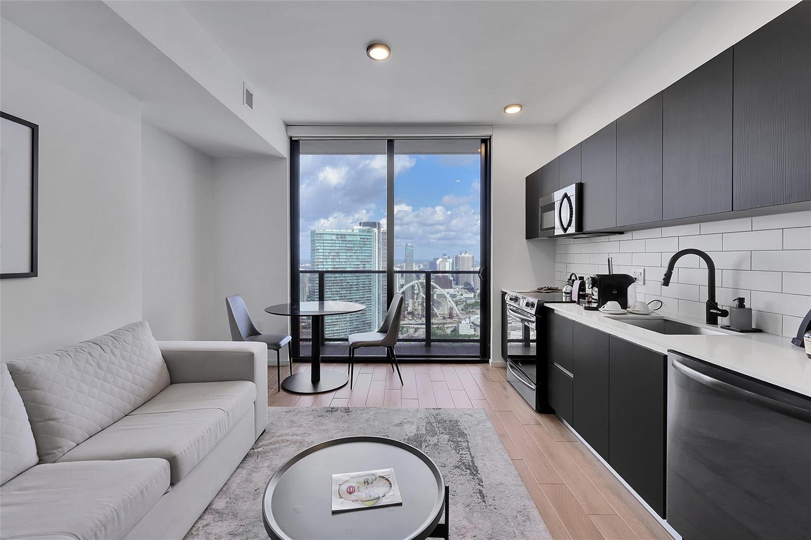 A modern studio apartment features a kitchen with dark cabinets, a sofa, and city views — 398 NE 5th Street # 4404, Miami FL 33132, MIAMI, FL