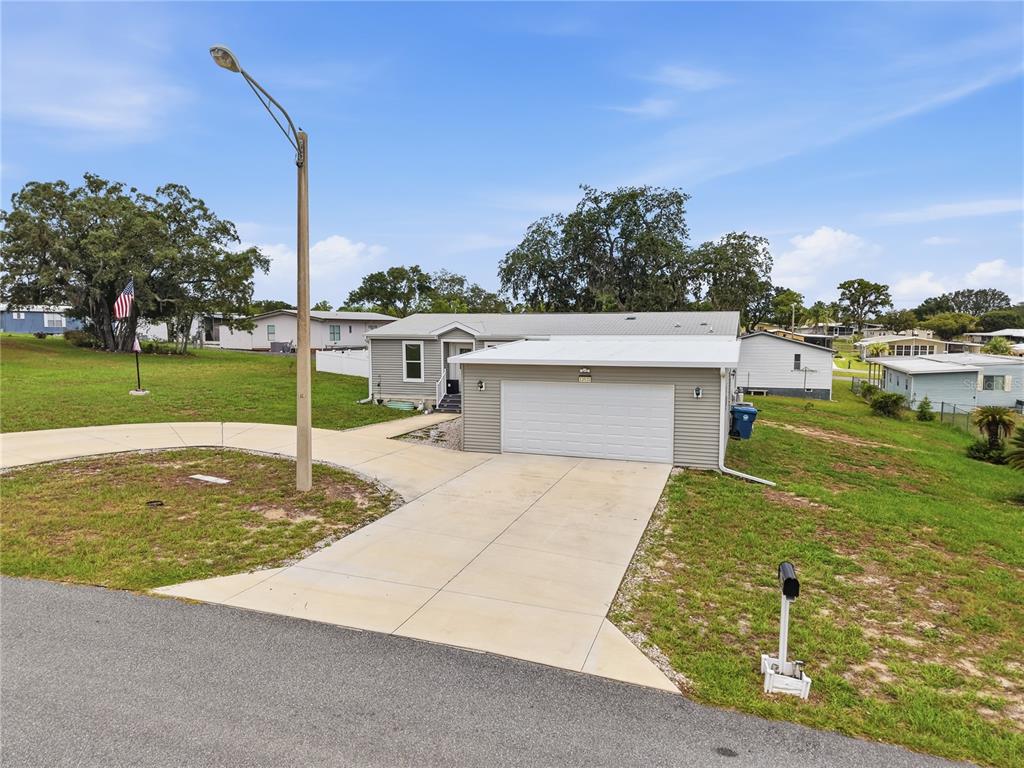 A single-story house with light gray siding and an attached garage sits on a lawn — 12532 FAIRWAY AVENUE, BROOKSVILLE, FL