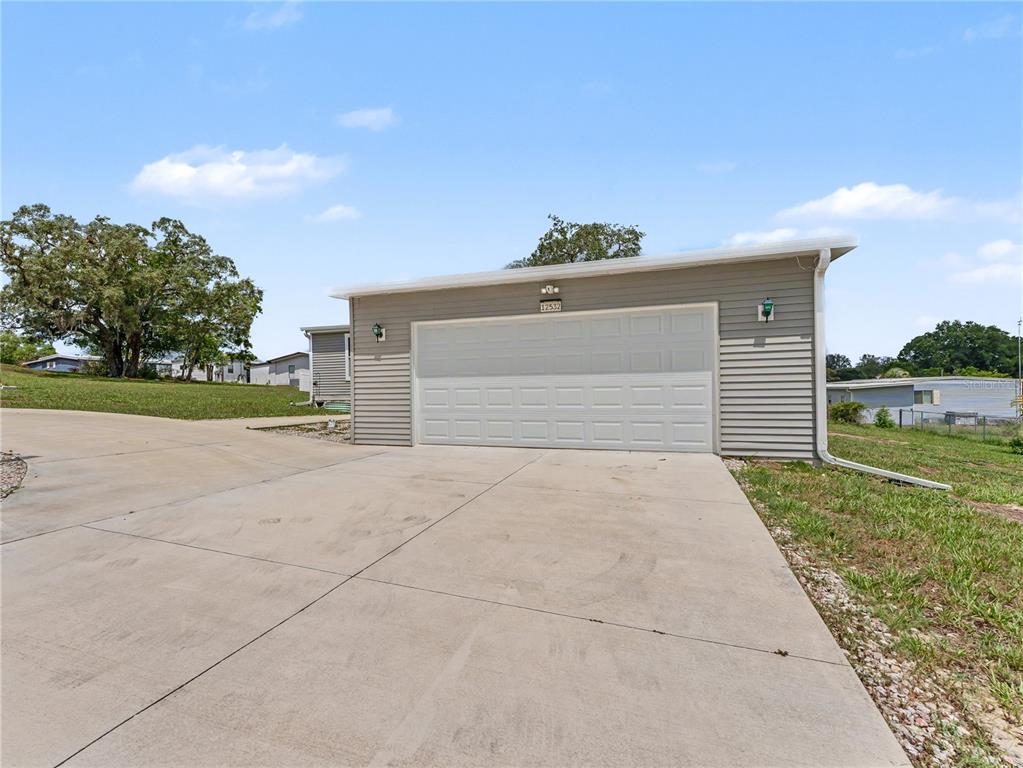 A detached garage with gray horizontal siding and a white sectional door sits on concrete — 12532 FAIRWAY AVENUE, BROOKSVILLE, FL