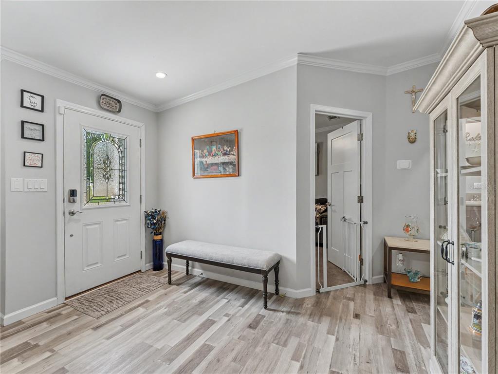 An entryway features light gray walls, wood-look flooring, a bench, and a white front door — 12532 FAIRWAY AVENUE, BROOKSVILLE, FL