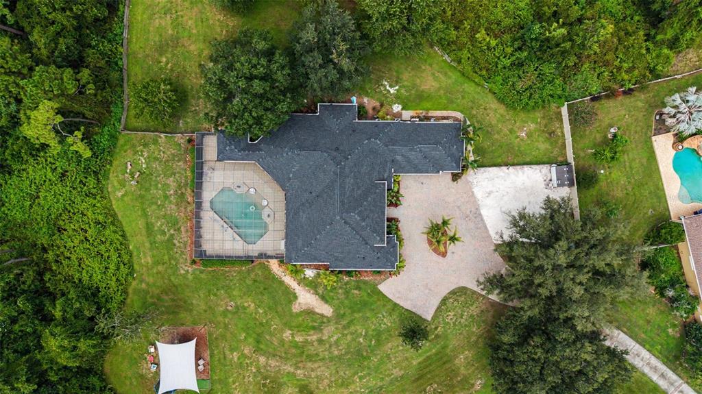 An aerial view shows a house with a screened pool, paved driveway, and surrounding yard — 15532 LAKE GRACE DRIVE, ODESSA, FL