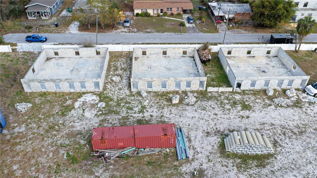 An aerial view shows three concrete block building foundations under construction on a dirt lot — 2909 E GENESEE STREET, TAMPA, FL