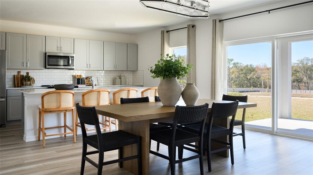 A kitchen and dining area featuring light gray cabinets, a wooden table, and sliding doors — 2358 STILLVIEW PASS, ZEPHYRHILLS, FL