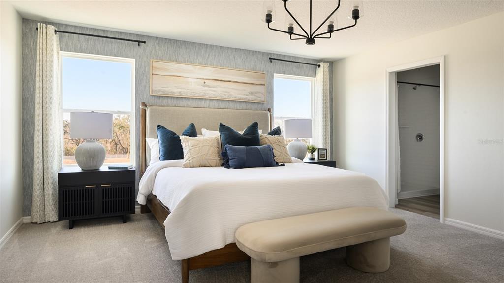 A bedroom features a bed with blue and beige pillows, a bench, and two windows — 2358 STILLVIEW PASS, ZEPHYRHILLS, FL
