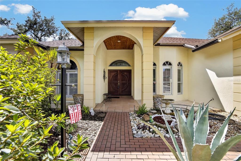 The exterior of a house features a brick walkway leading to a covered arched entryway — 2704 ASTON AVENUE, PLANT CITY, FL