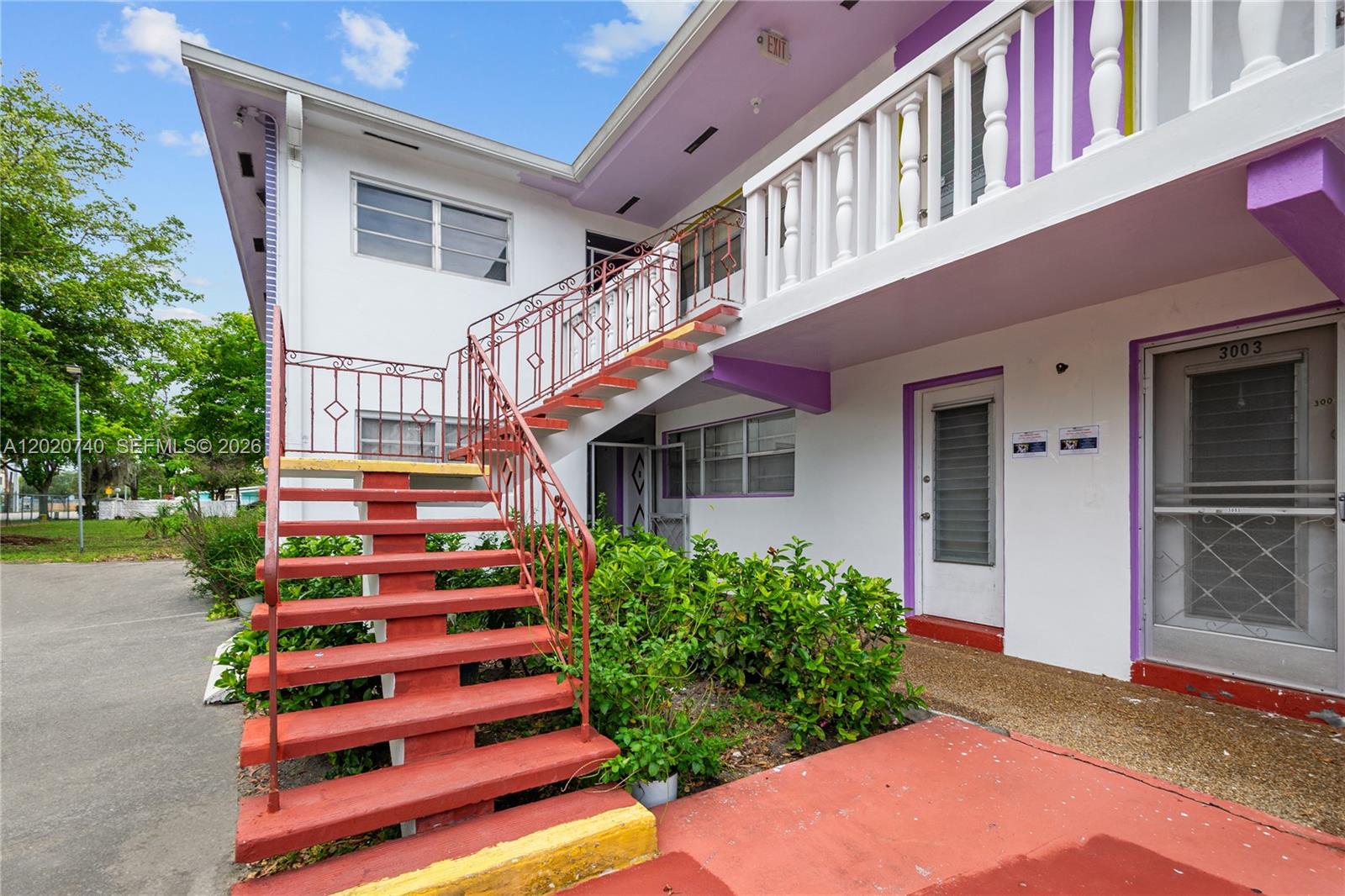 An exterior view of a two-story apartment building with red stairs and purple accents — 245 NE 191st St # 3014, Miami FL 33179, MIAMI, FL
