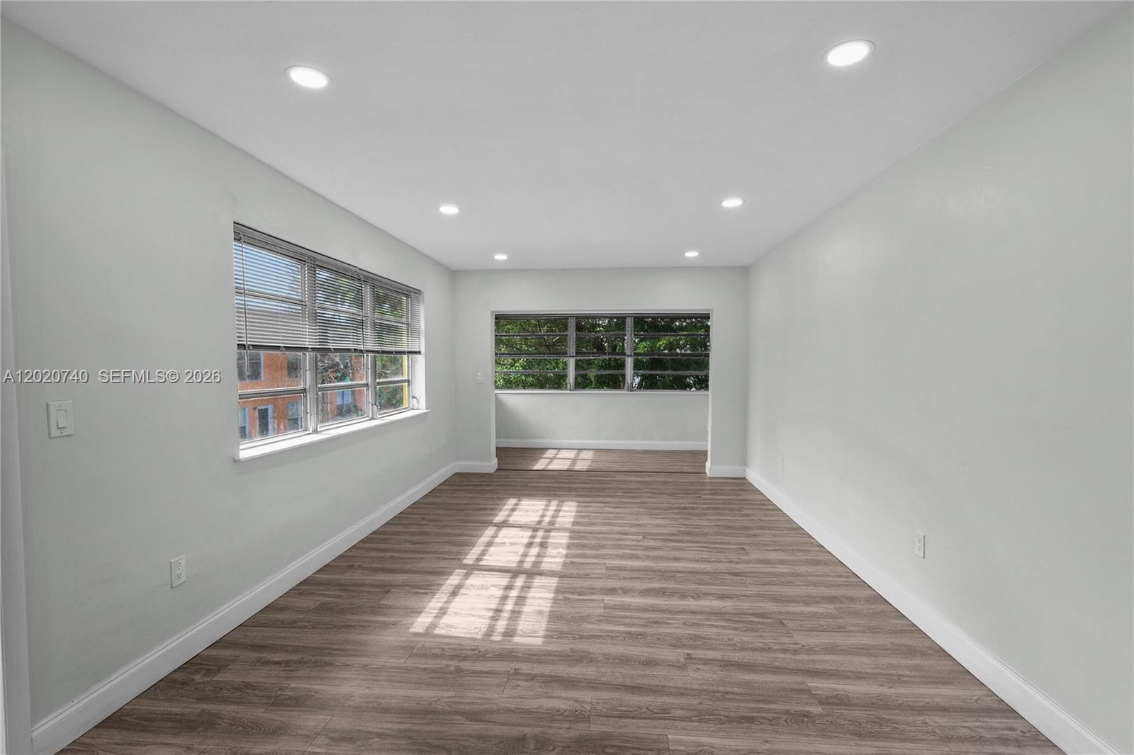 An empty room features light gray walls, recessed lighting, and wood-look flooring — 245 NE 191st St # 3014, Miami FL 33179, MIAMI, FL