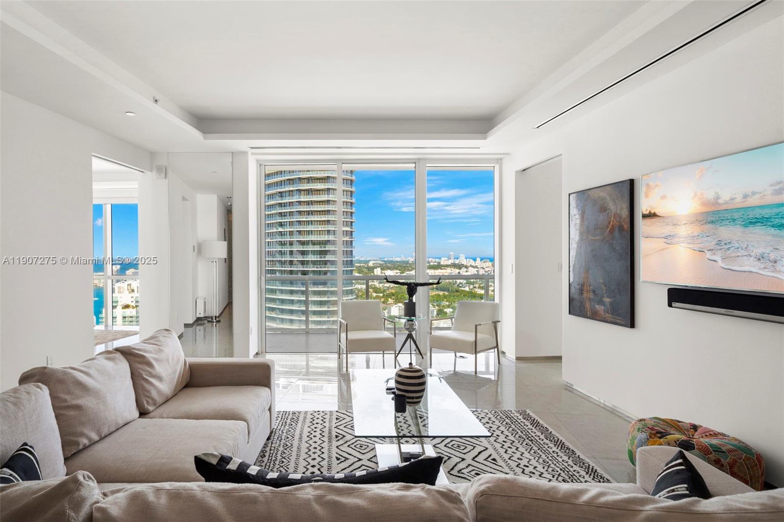 A modern living room features a beige sectional, glass coffee table, and floor-to-ceiling windows — 450 Alton Rd # 4104, Miami Beach FL 33139, MIAMI BEACH, FL