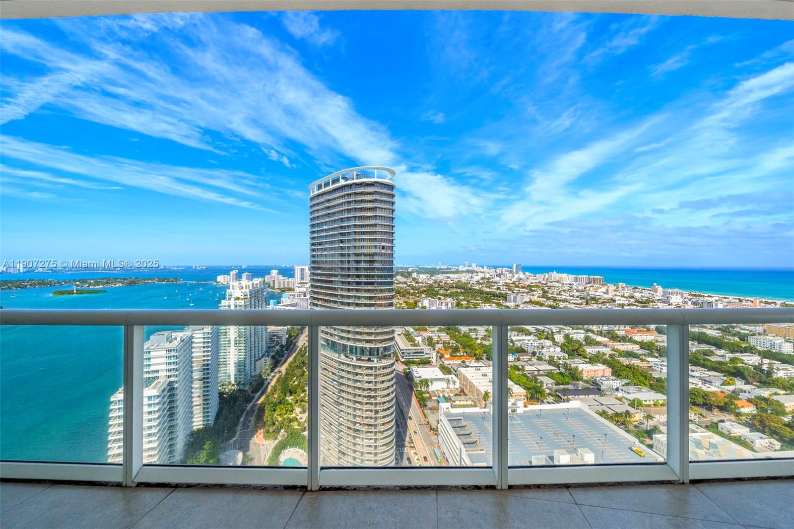A high-rise balcony overlooks a city skyline, a large circular tower, and the ocean — 450 Alton Rd # 4104, Miami Beach FL 33139, MIAMI BEACH, FL