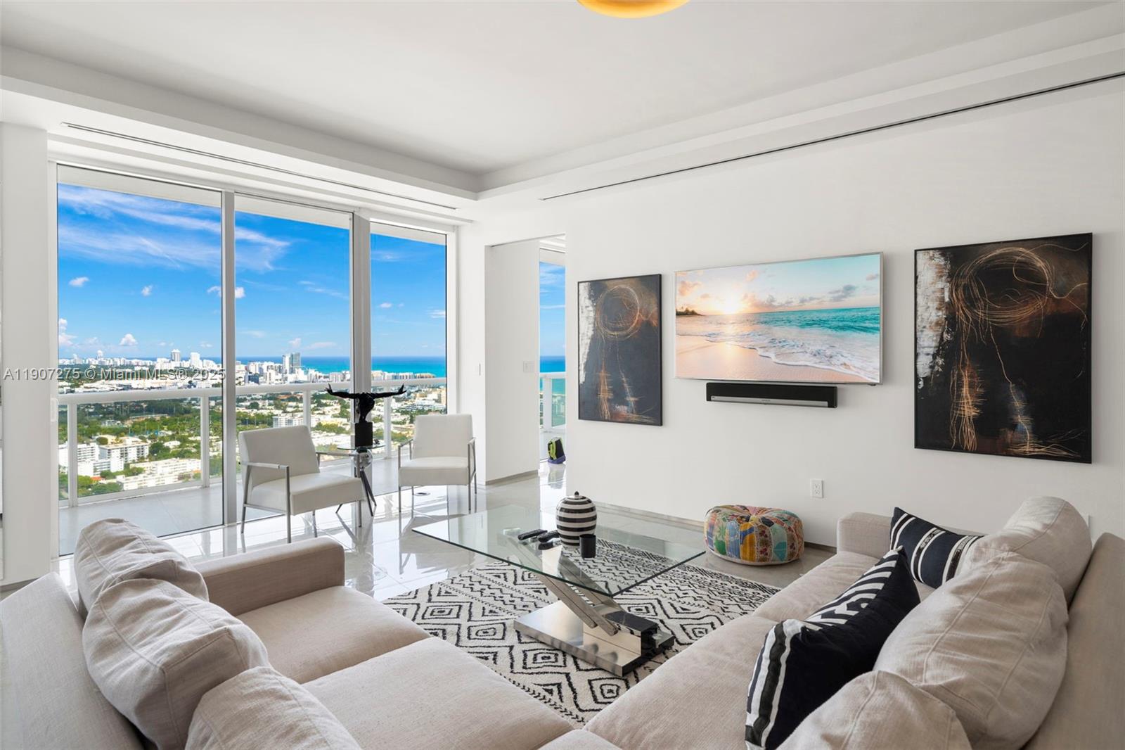 A modern living room features a white sofa, glass coffee table, and floor-to-ceiling windows — 450 Alton Rd # 4104, Miami Beach FL 33139, MIAMI BEACH, FL