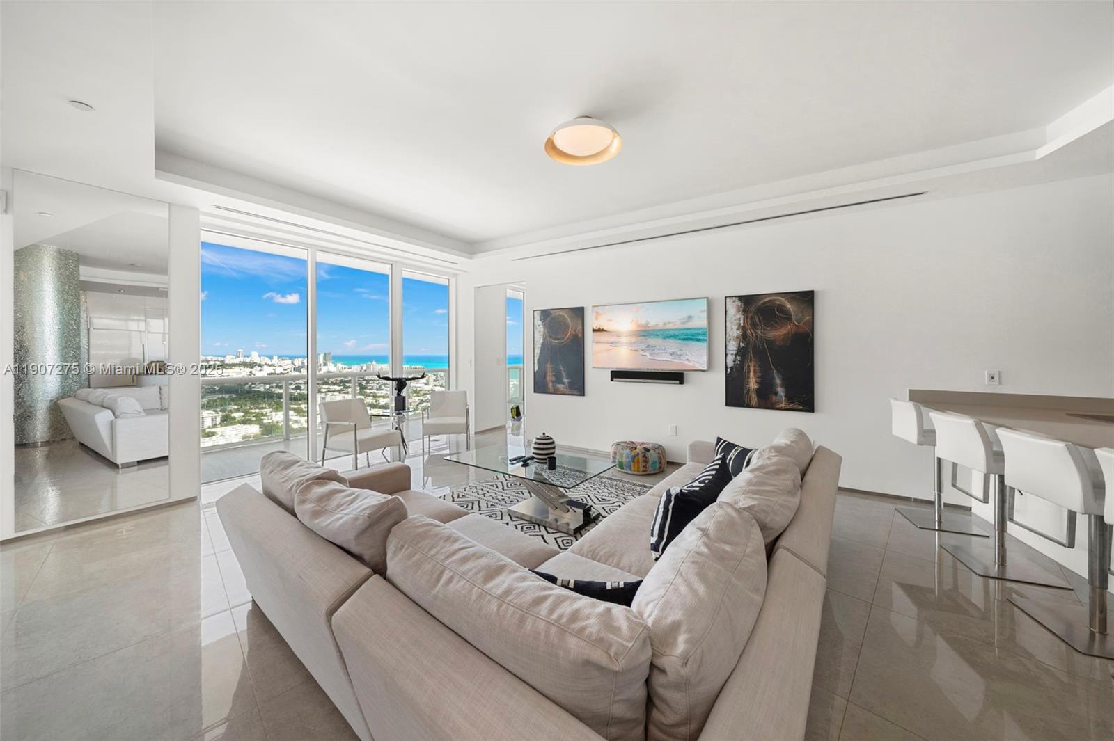 A modern living room features a large sectional sofa, glass coffee table, and floor-to-ceiling windows — 450 Alton Rd # 4104, Miami Beach FL 33139, MIAMI BEACH, FL