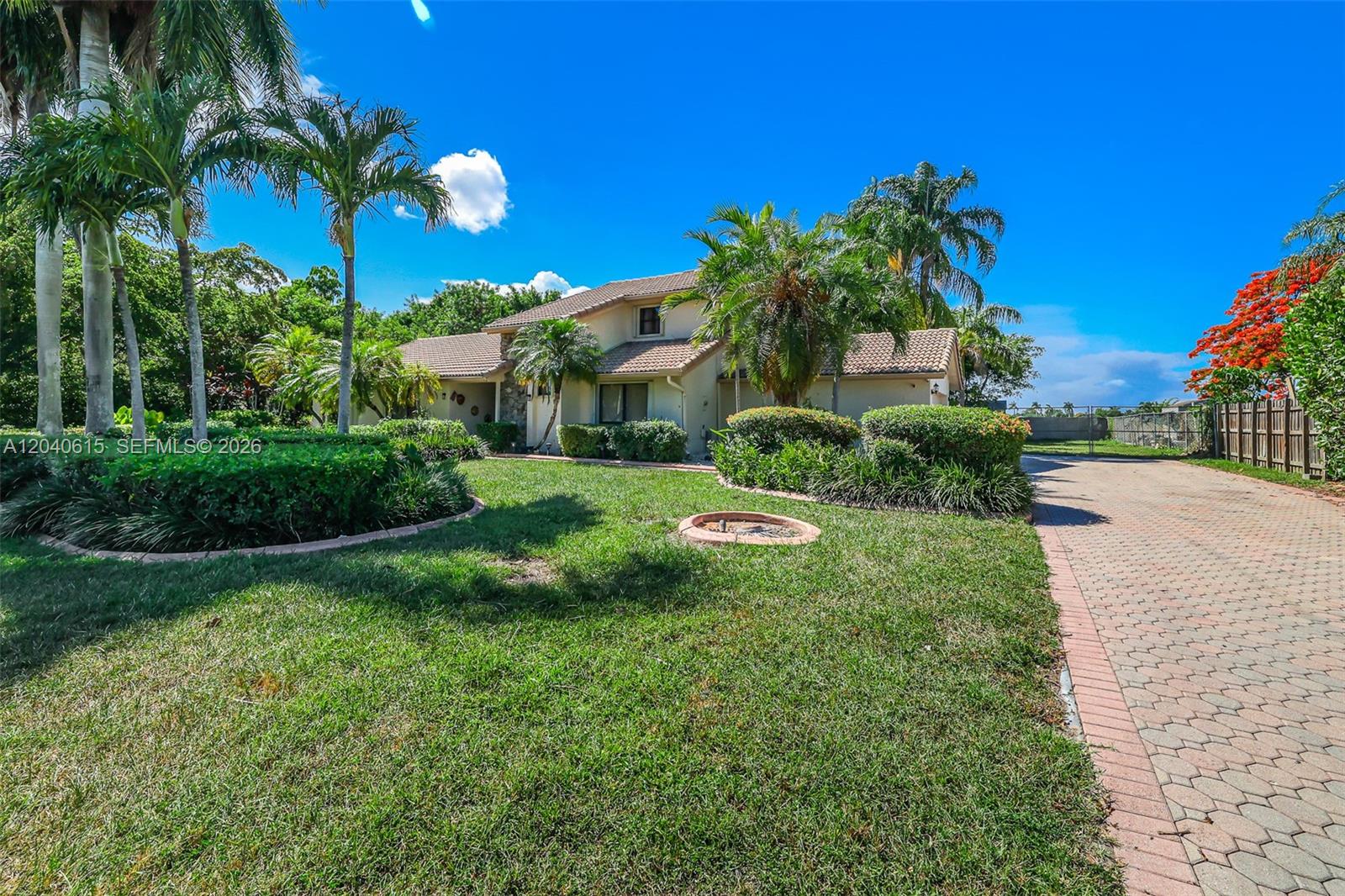 A two-story house with a tiled roof sits behind a lawn and paved driveway — 14941 SW 164th Ter, Miami FL 33187, MIAMI, FL