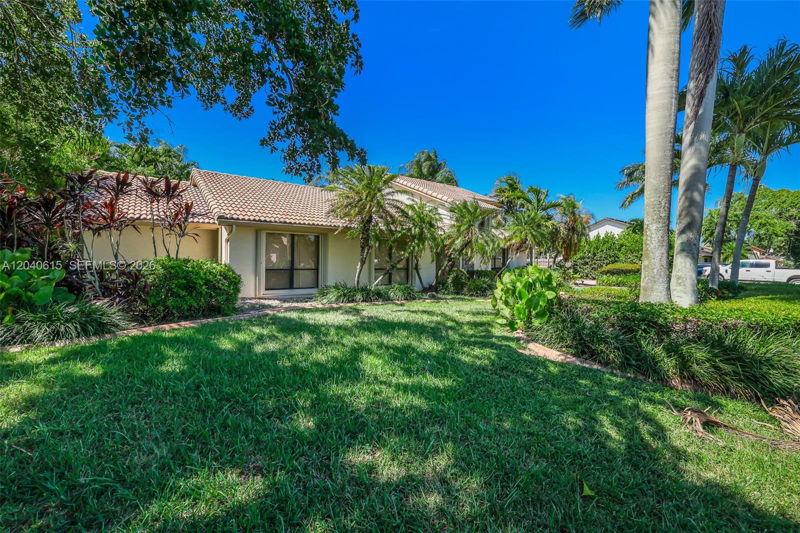 A single-story house with a tiled roof sits behind a green lawn and palm trees — 14941 SW 164th Ter, Miami FL 33187, MIAMI, FL